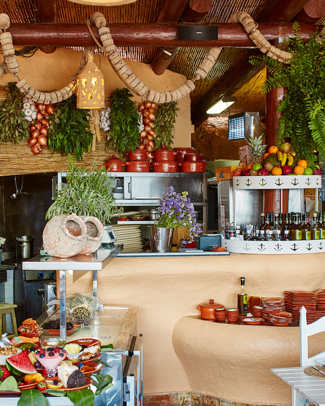 Zona de balcão do restaurante com decoração de alhos, cebolas e exposição de frutas e sobremesas.